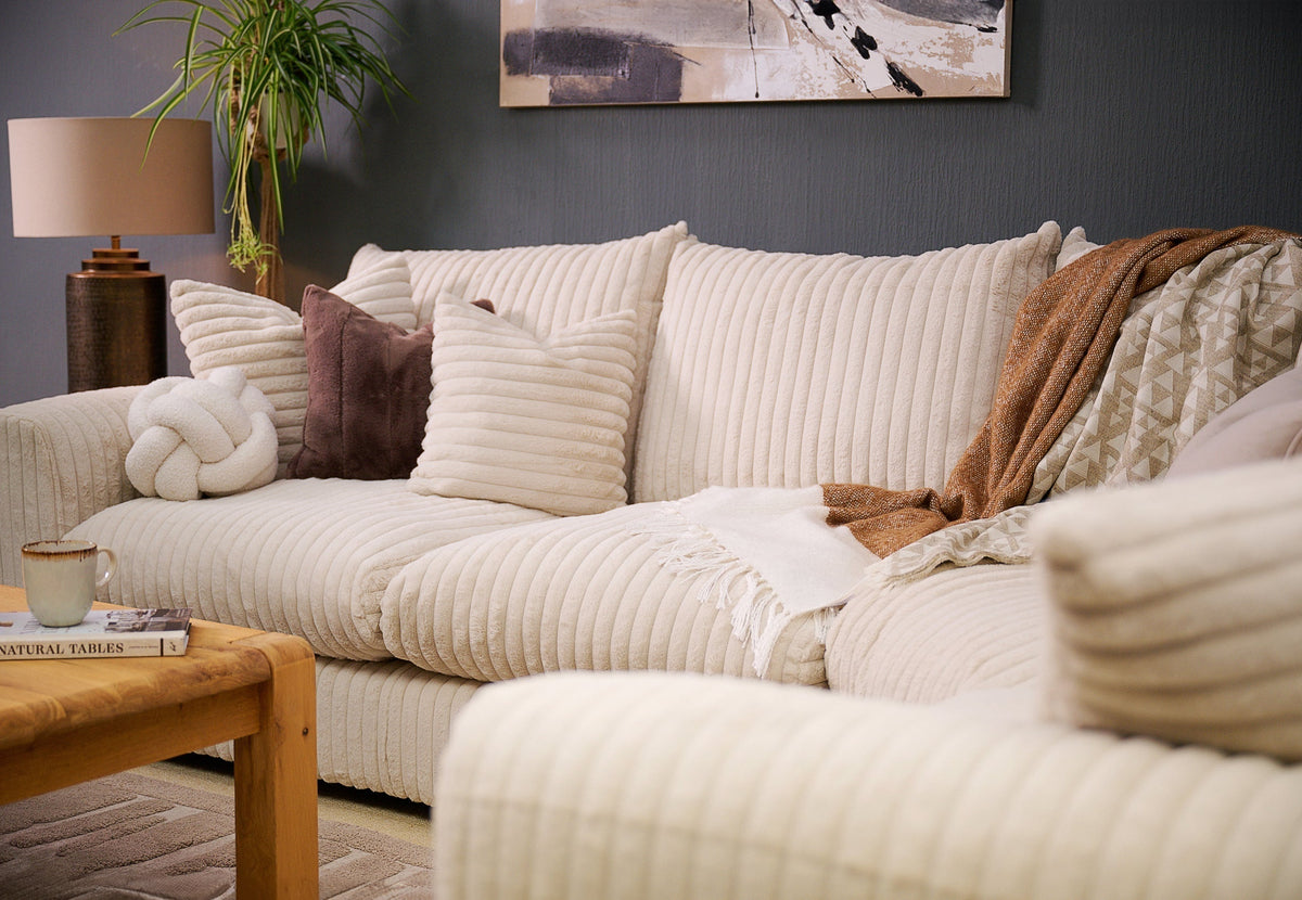 white soft and fluffy fabric sofa with brown cushions and throws 