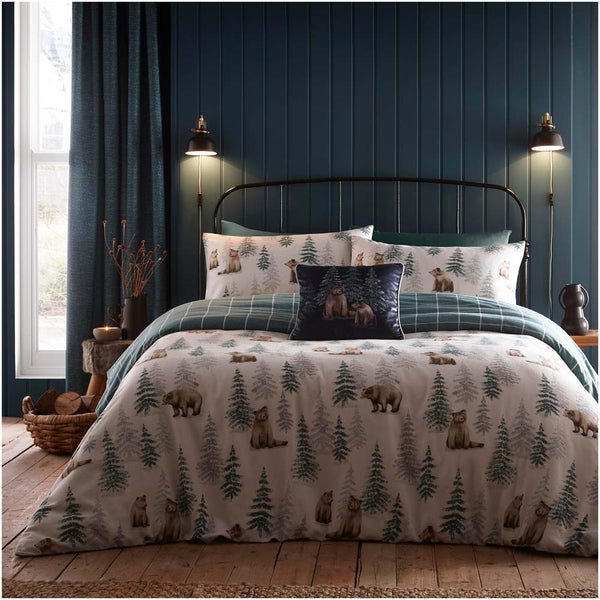 Bedroom with a bed featuring a forest-themed comforter and pillows against a dark blue paneled wall.
