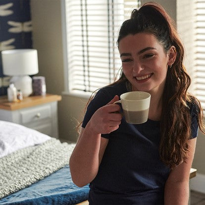 Woman holding a mug in a bedroom setting