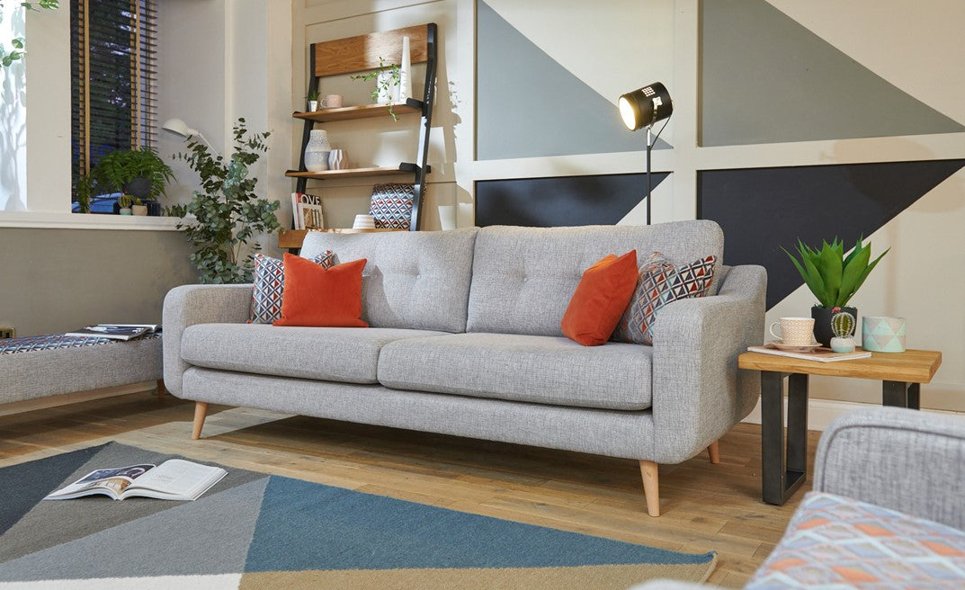 Large grey sofa with orange cushions in a living room setting.
