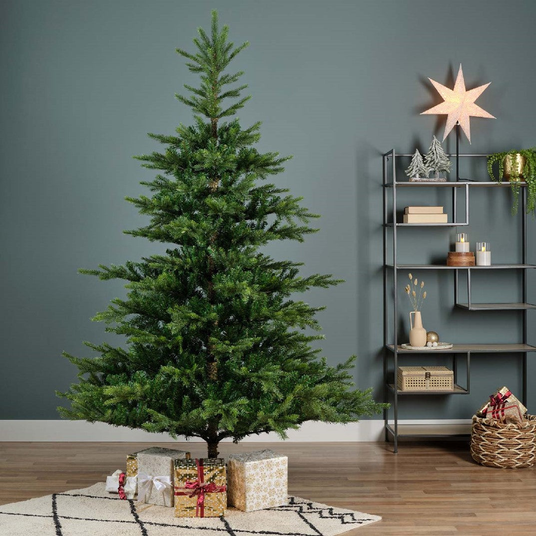 Decorative Christmas tree with presents in a room with a shelf and star decoration.