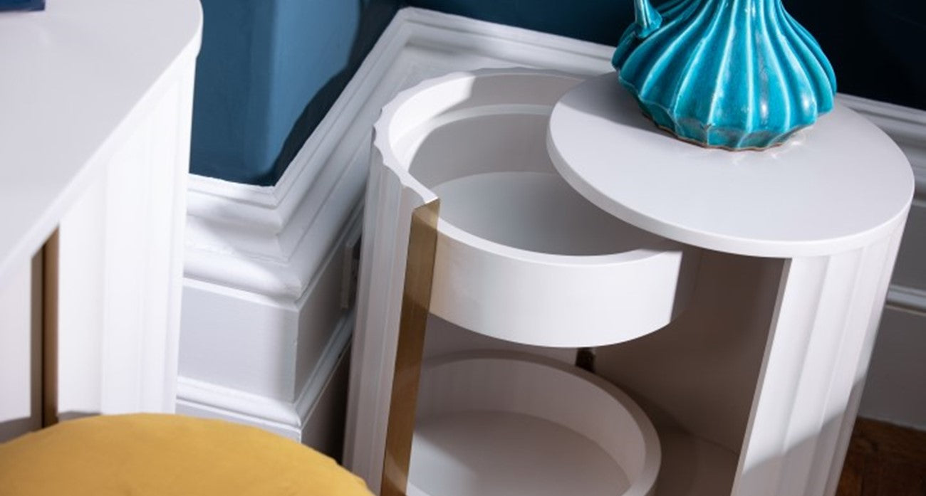 white bedside table with hidden storage and a blue vase on top.