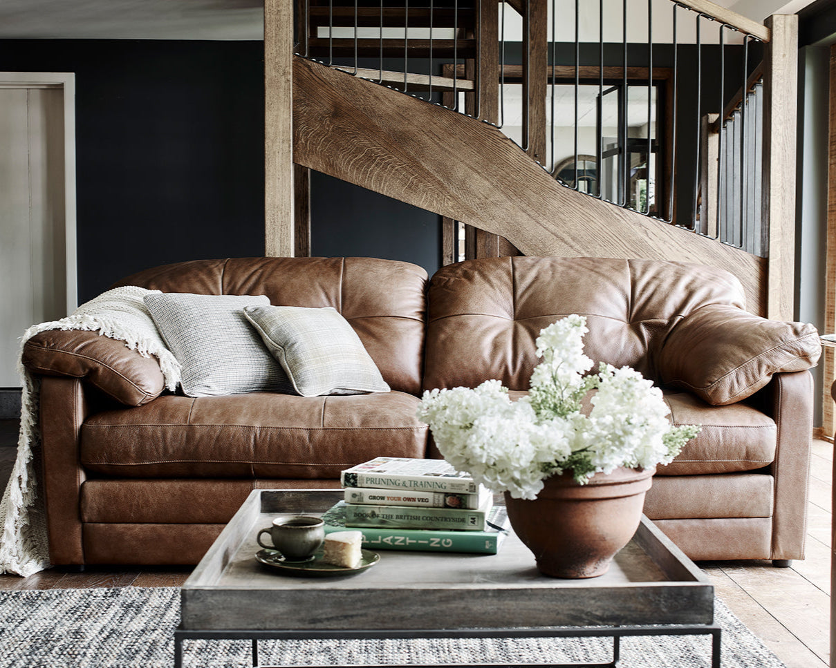 Brown leather sofa in a living room with a coffee table and decorative items.