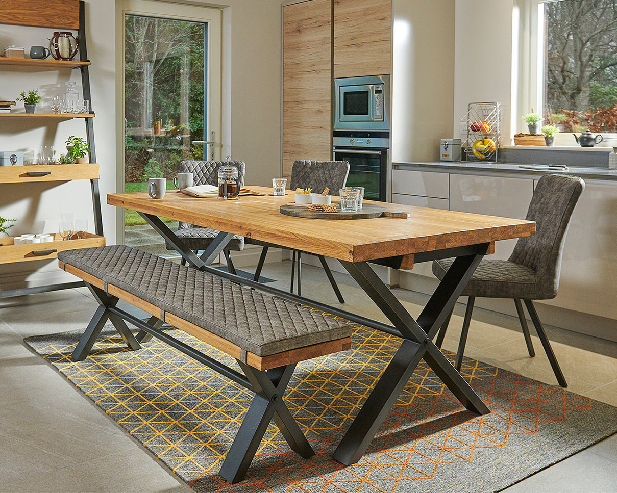 Modern kitchen with wooden dining table and bench, shelves, and appliances.
