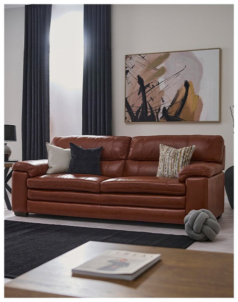 Brown leather sofa in a living room with abstract art on the wall.
