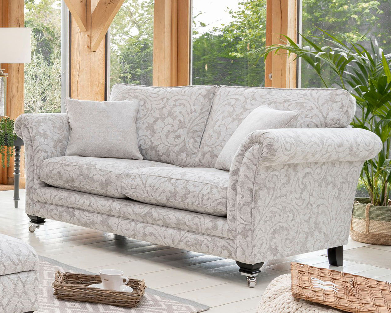 Patterned sofa in a bright living room with large windows and plants.