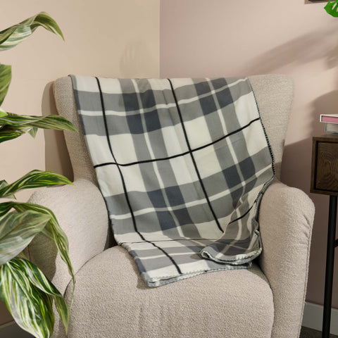 Plaid blanket draped over a chair with a plant and side table in the background