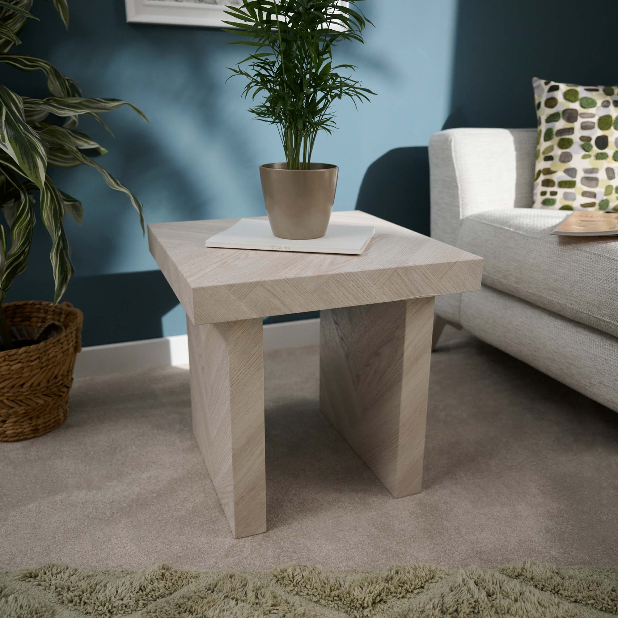 Beige stone side table with a plant in a living room setting