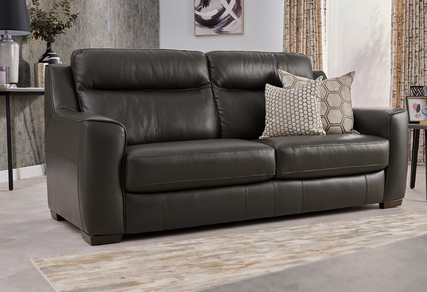 black leather sofa with decorative pillows in a living room setting.