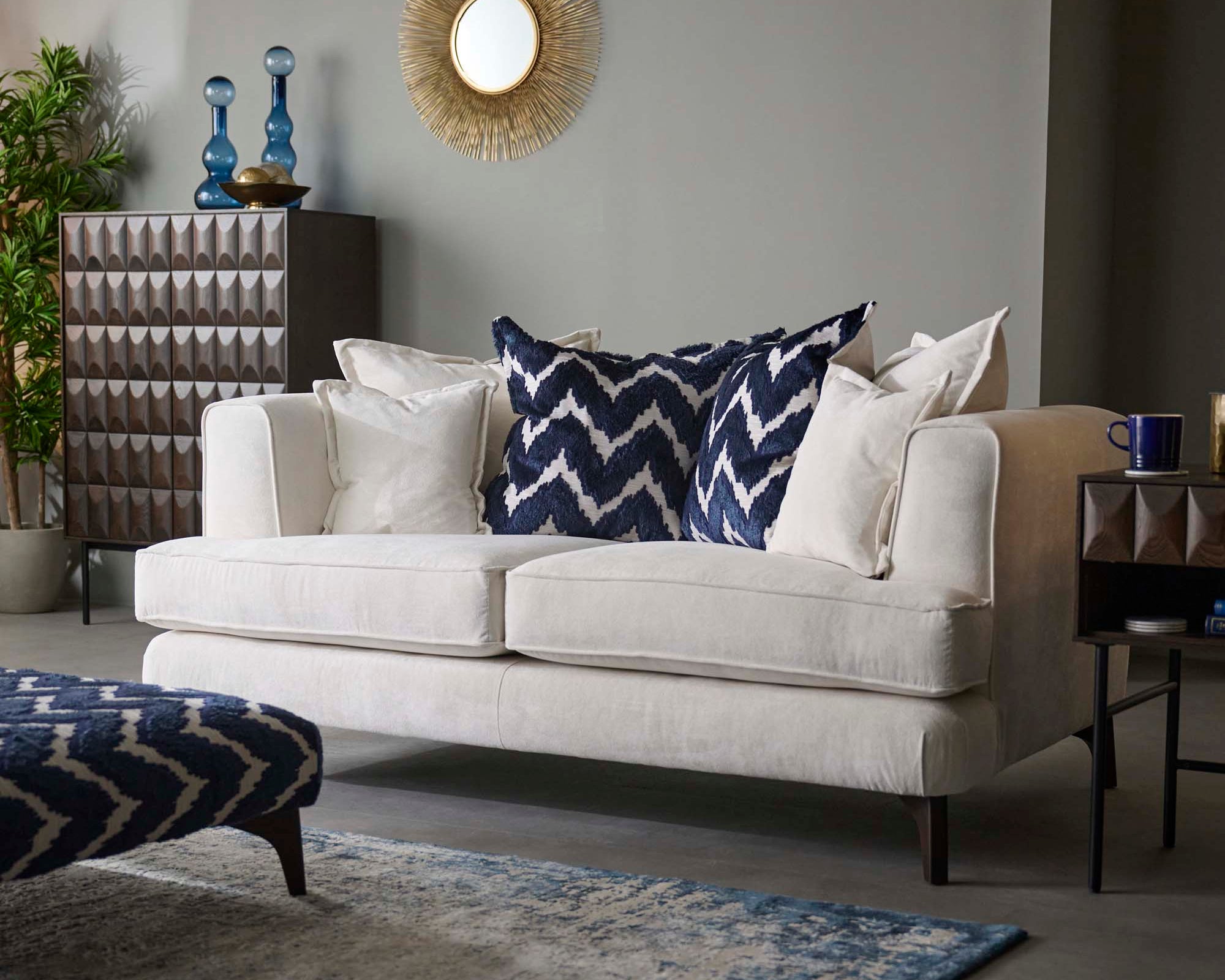 Living room with a Faith white sofa, blue and white patterned pillows, and a rug.