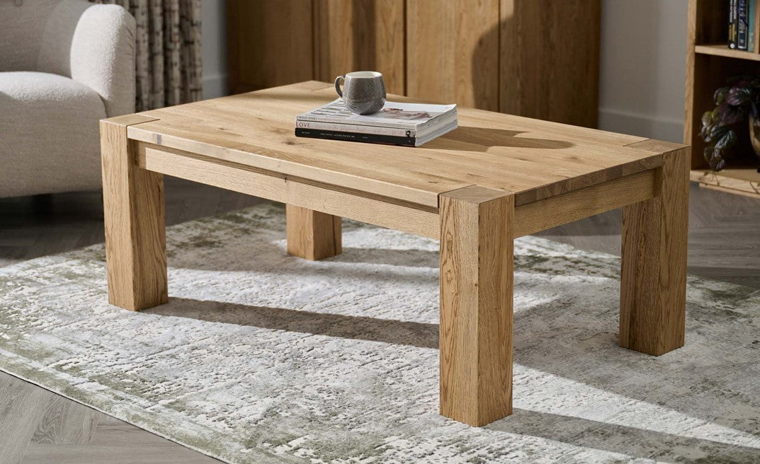 Wooden coffee table with a book and mug on a rug in a room setting
