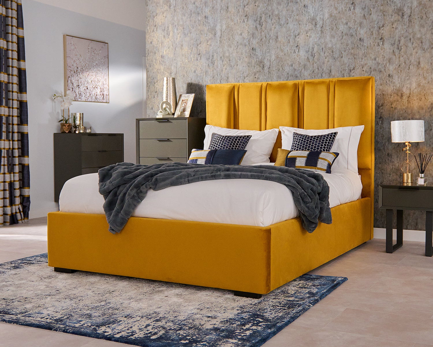 Yellow bed with white bedding and grey blanket in a bedroom setting.