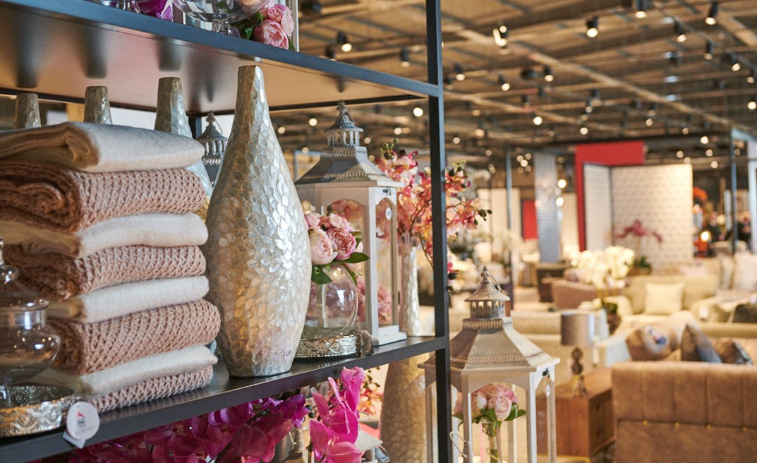 Decorative items on a shelf in a home decor store with various products in the background.