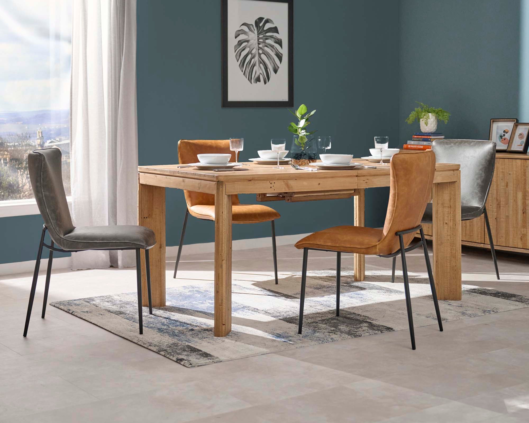 Dining room with wooden table and chairs against a blue wall.