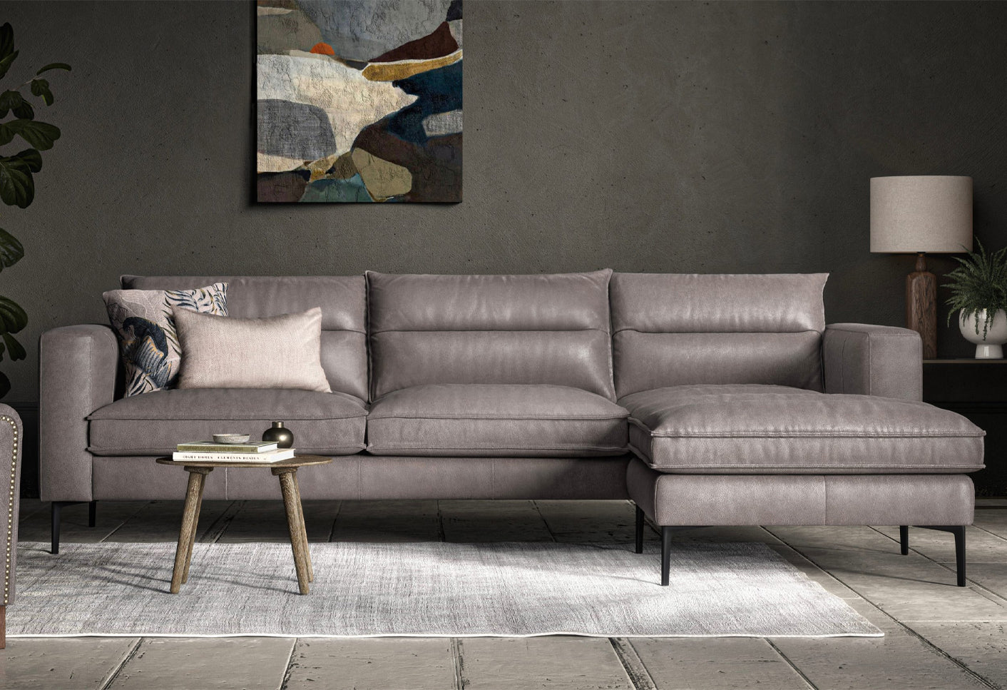 Grey leather chaise sofa in a living room setting with an abstract painting on the wall.