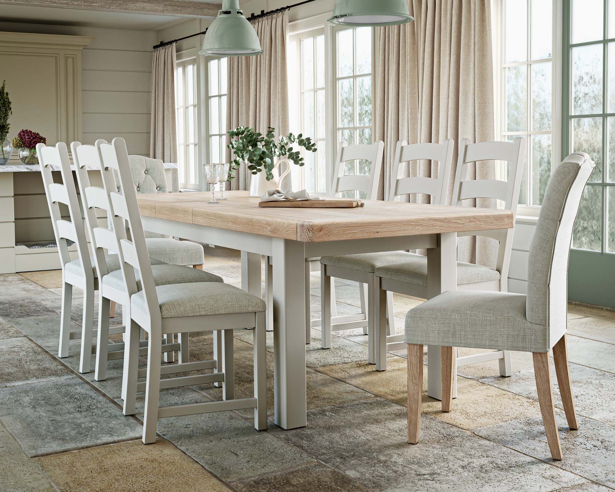 Dining room with wooden table and white chairs in a bright room.