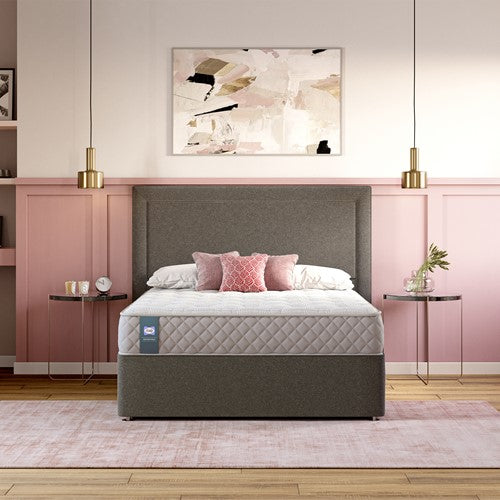 Bedroom with a Sealy gray bed frame and mattress against a pink wall.