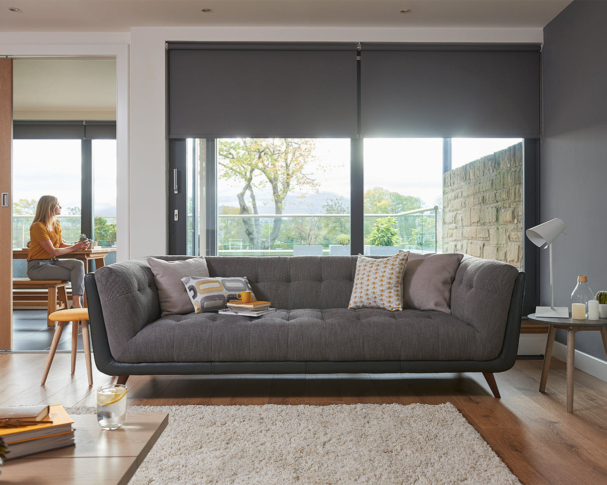 Modern living room with a grey sofa, coffee table, and large windows.
