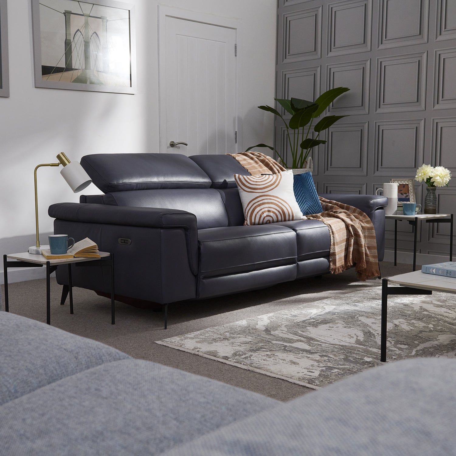 Modern living room with a Sparta dark blue leather sofa, decorative pillows, and a stylish rug.