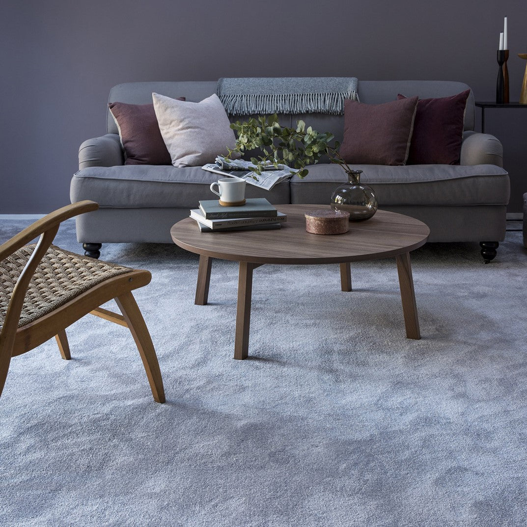 Living room with a grey sofa, wooden coffee table, and armchair on a soft grey carpet.