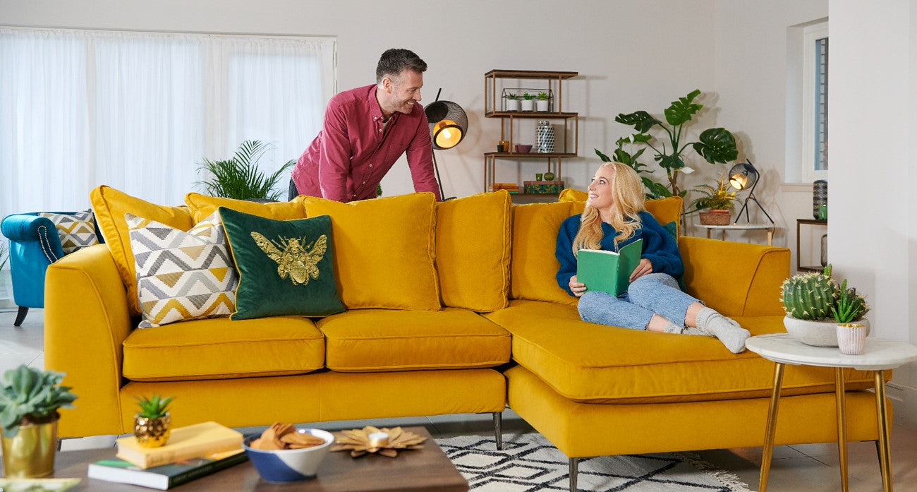 Colourful living room with a yellow corner  sofa, plants, and a coffee table.