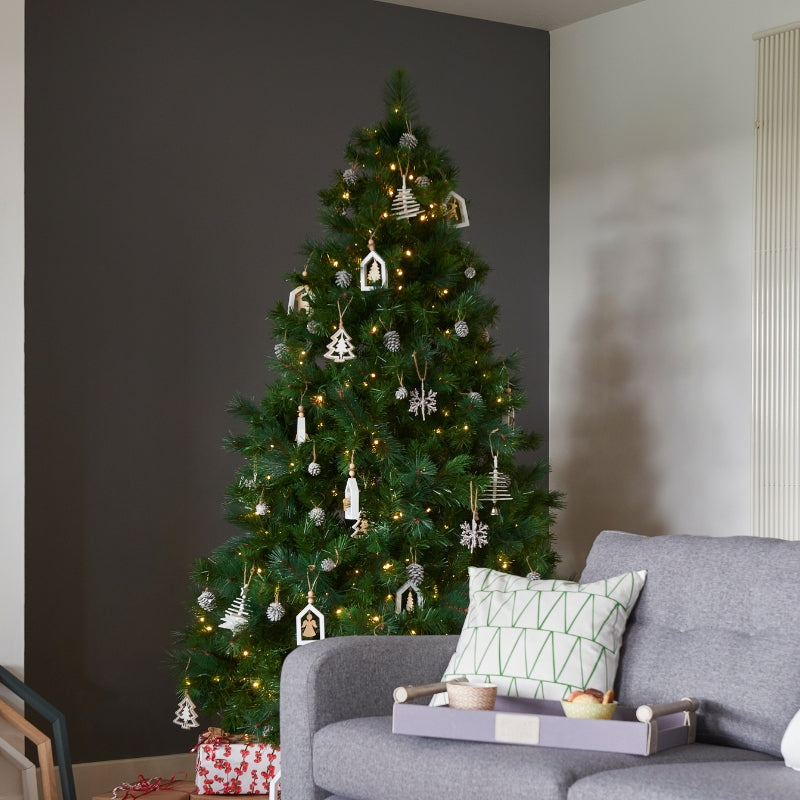Decorated Christmas tree in a living room with a gray sofa and festive decor.