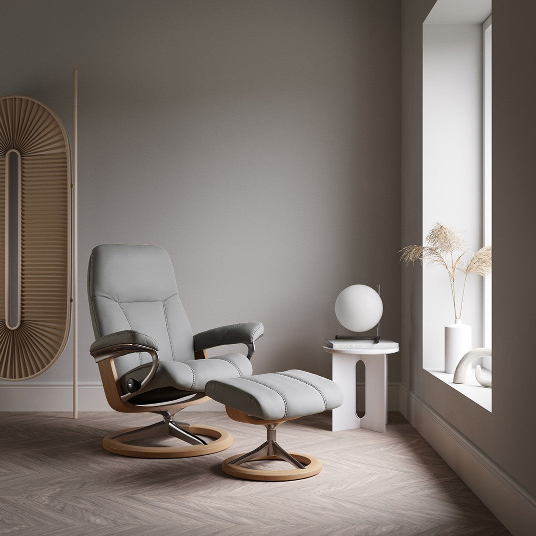 Cream leather recliner chair in a with foot stool and wooden base.