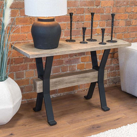 Wooden table with black metal legs against a brick wall