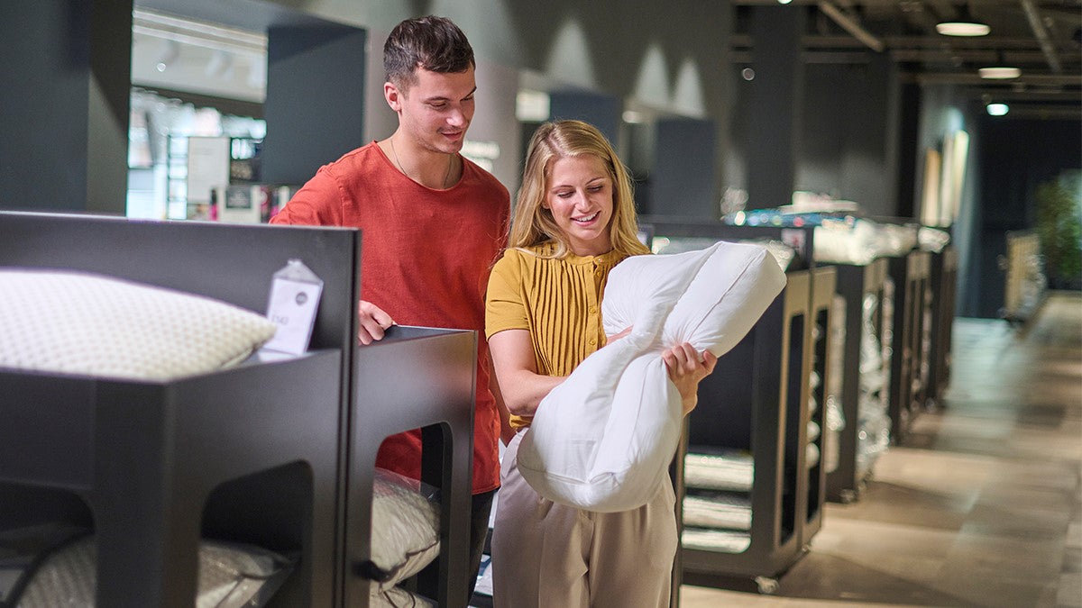 Two people in store looking at bed pillows