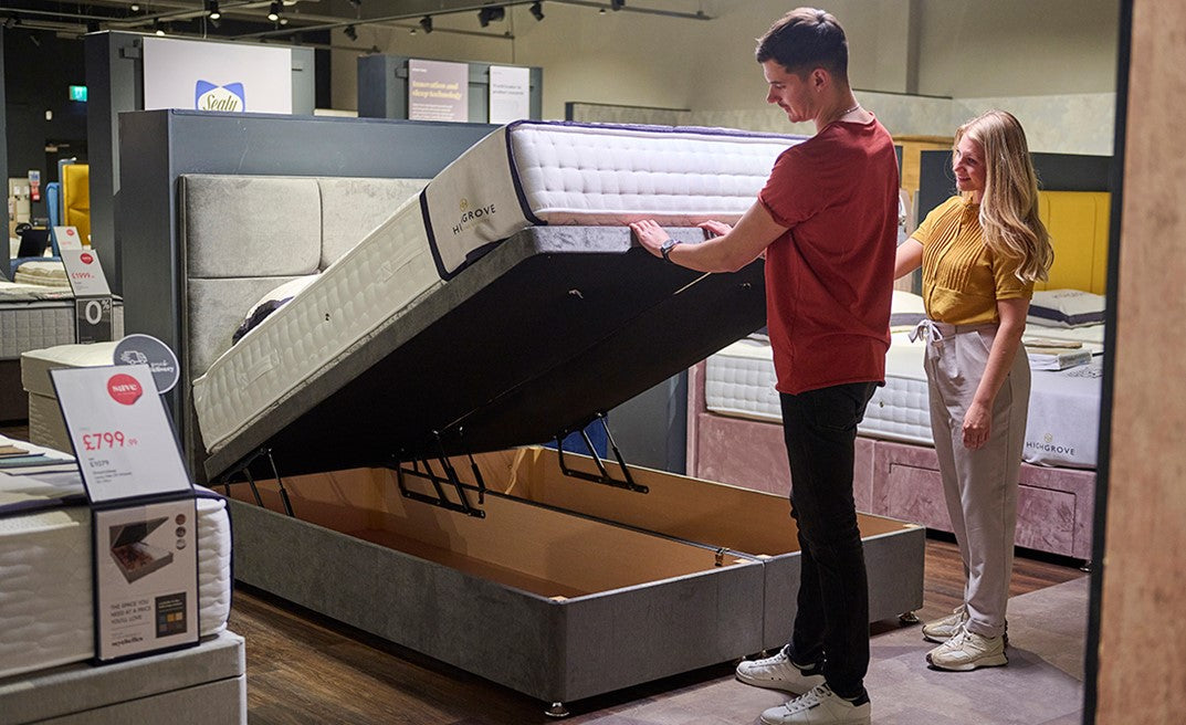 A man and a woman looking at an ottoman bed.