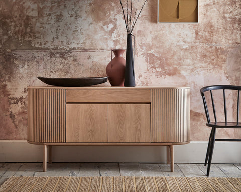 Wooden sideboard against a textured wall with a window and decorative elements.