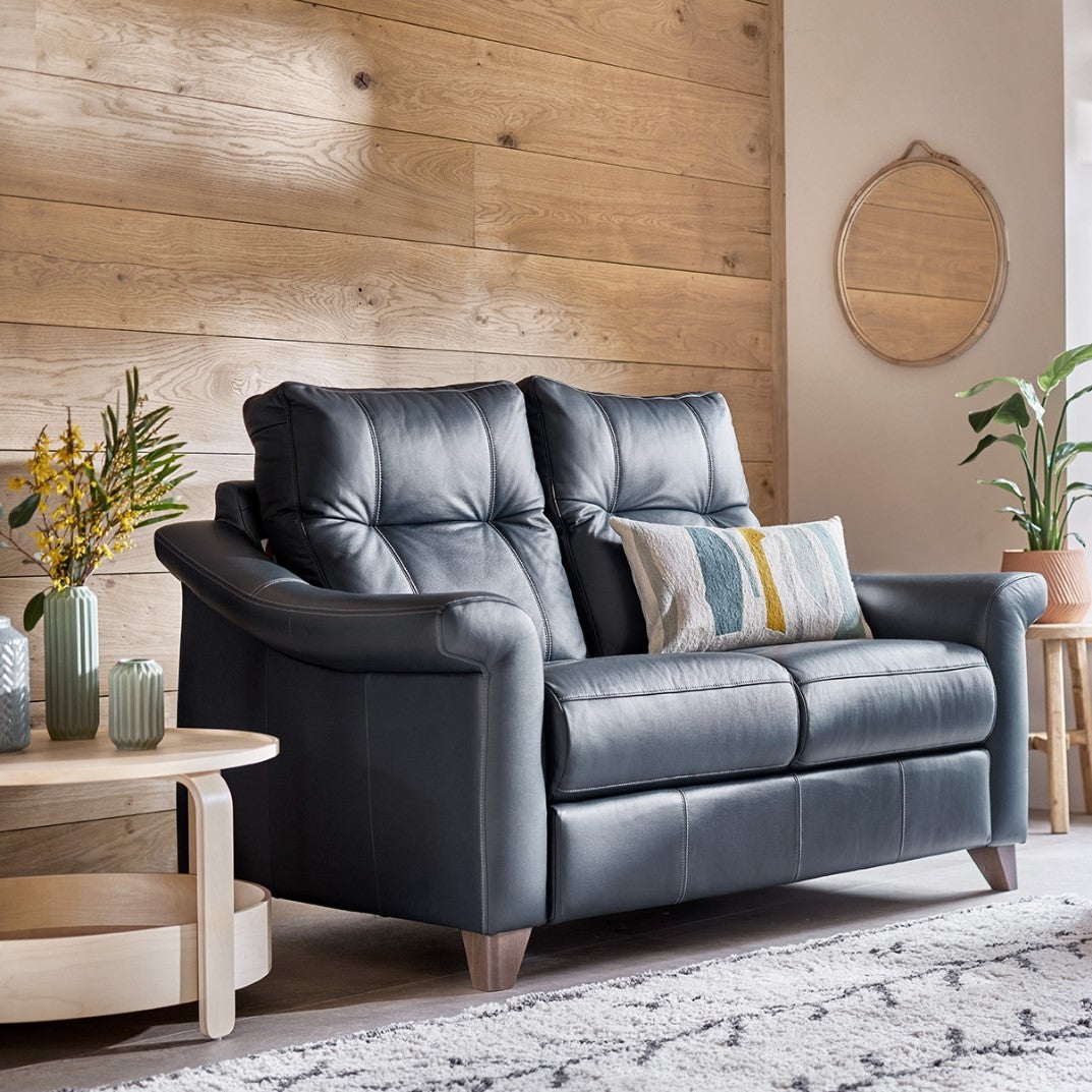 Black leather sofa in a living room with wooden walls and decor