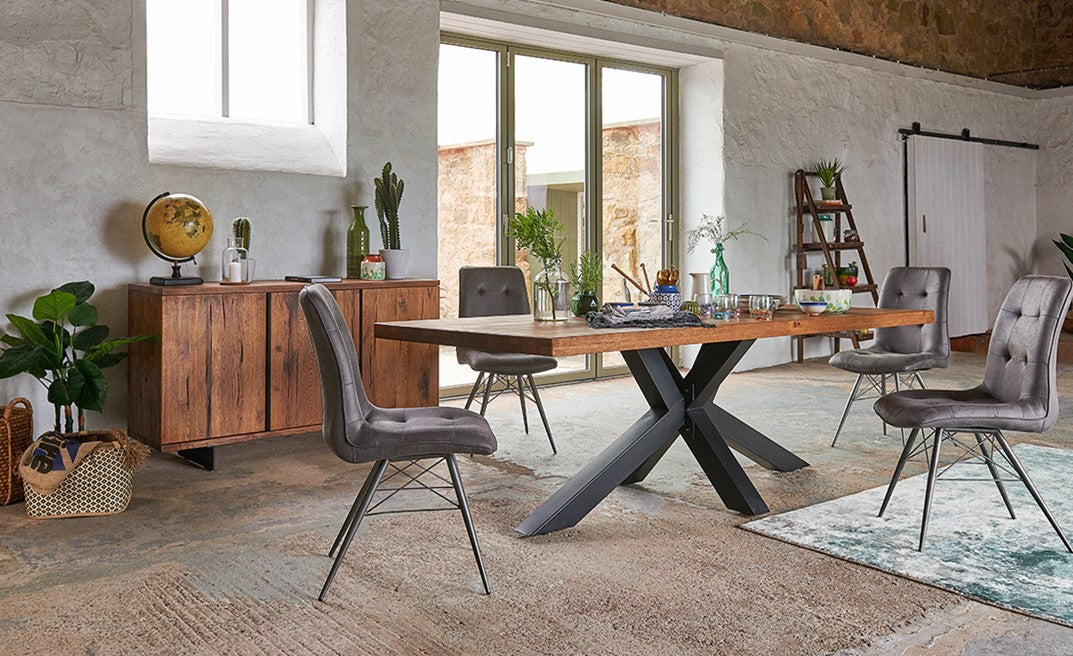 Modern dining room with wooden table, gray chairs, and wooden sideboard, featuring kitchenware on dining table.