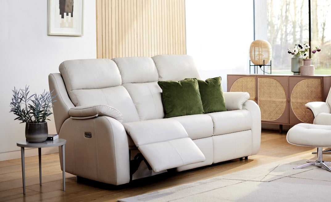 3 seater leather recliner sofa in a living room setting with green pillows and decorative items.