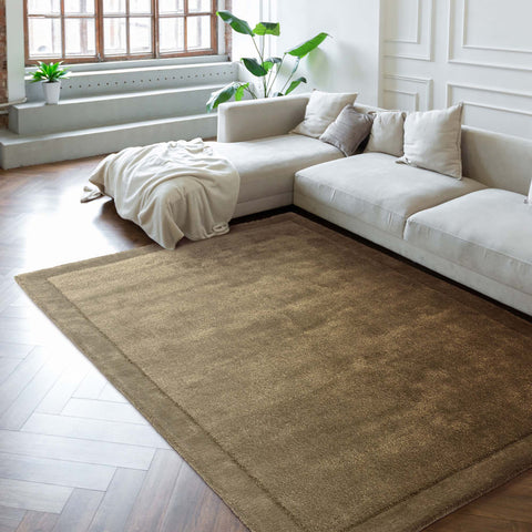 Beige rug on a wooden floor in a living room with a white sofa and plants.