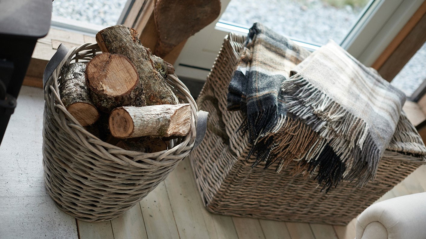 Wicker baskets with logs and a plaid blanket.