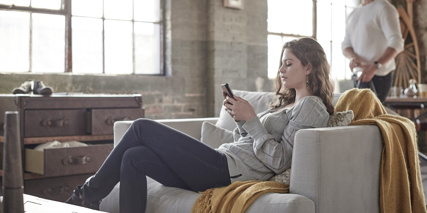 Woman sitting on a couch using a smartphone in a modern living room.