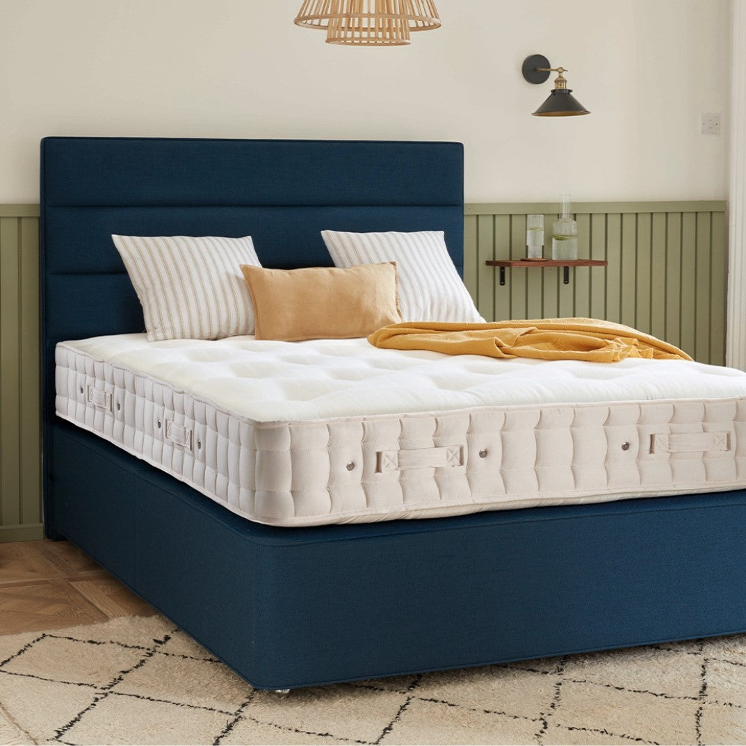 Blue bed fabric  bed frame with white mattress, pillows, and a blanket in a room setting.
