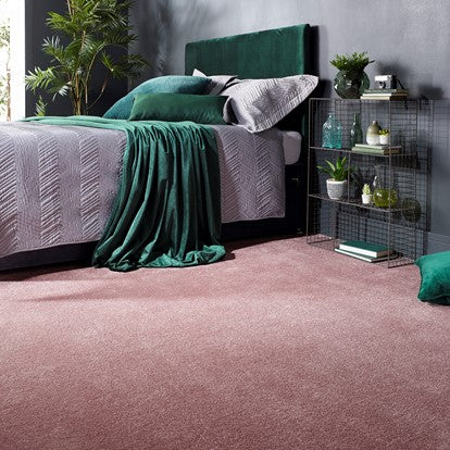 Bedroom with a green velvet bed, green pillows, and pink carpet. 