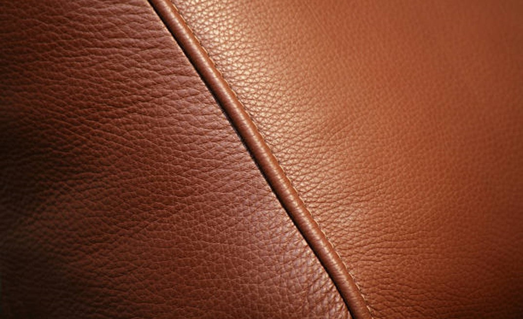 Close-up of brown leather texture with a visible seam