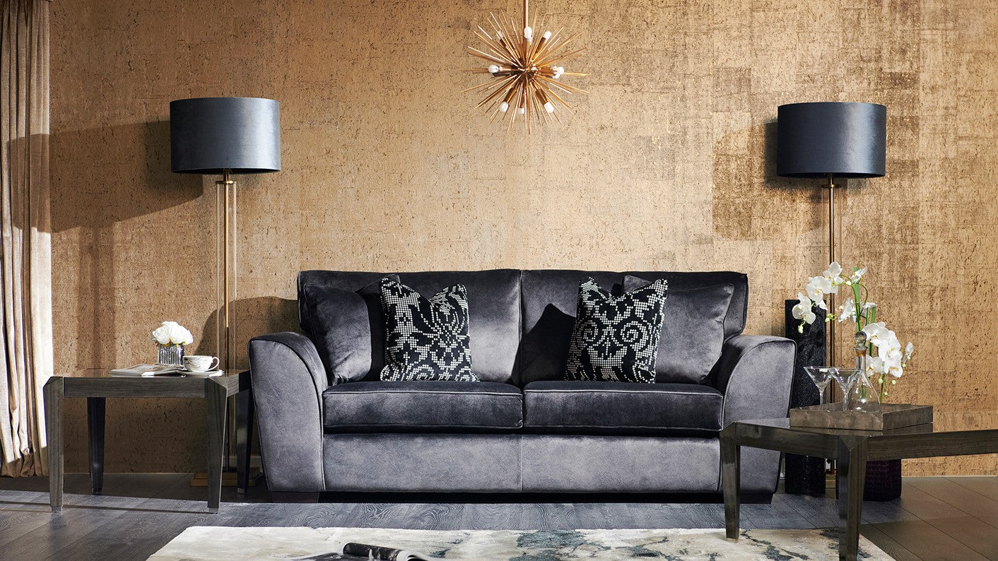 Grey 2 seater sofa in a living room with decorative pillows, coffee table, lamps, and a rug.