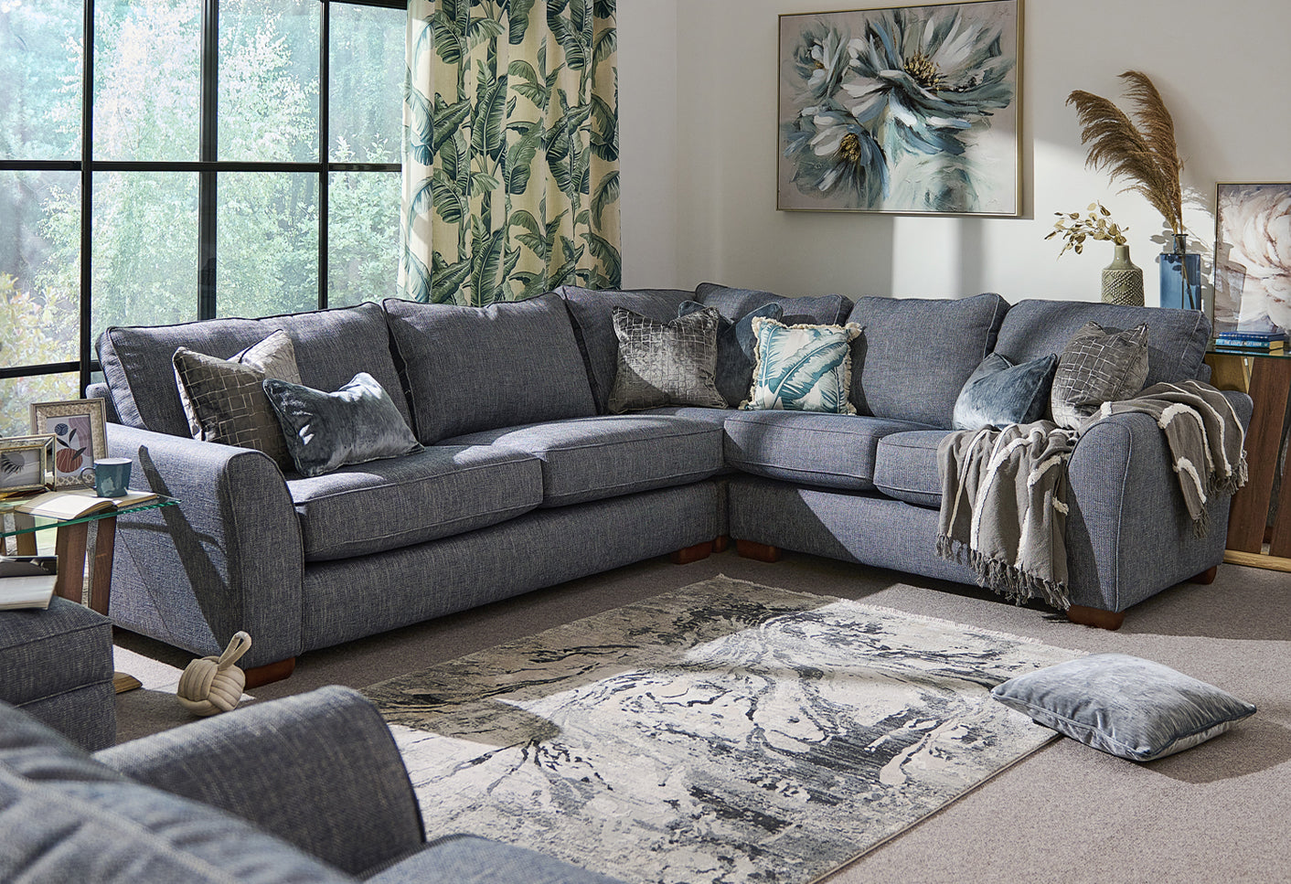 Grey sectional sofa in a living room with decorative pillows and a rug.