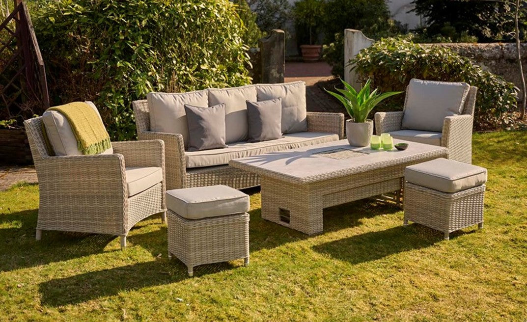 Outdoor garden furniture set on a grassy area with plants and a garden.