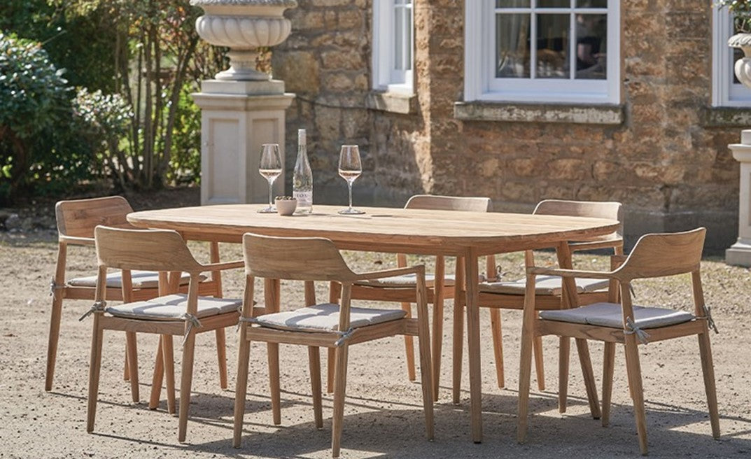 Outdoor dining set with wooden table and chairs in a garden setting.