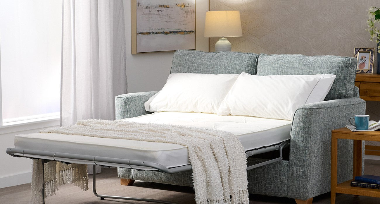 Grey sofa bed with white pillows in a living room setting.