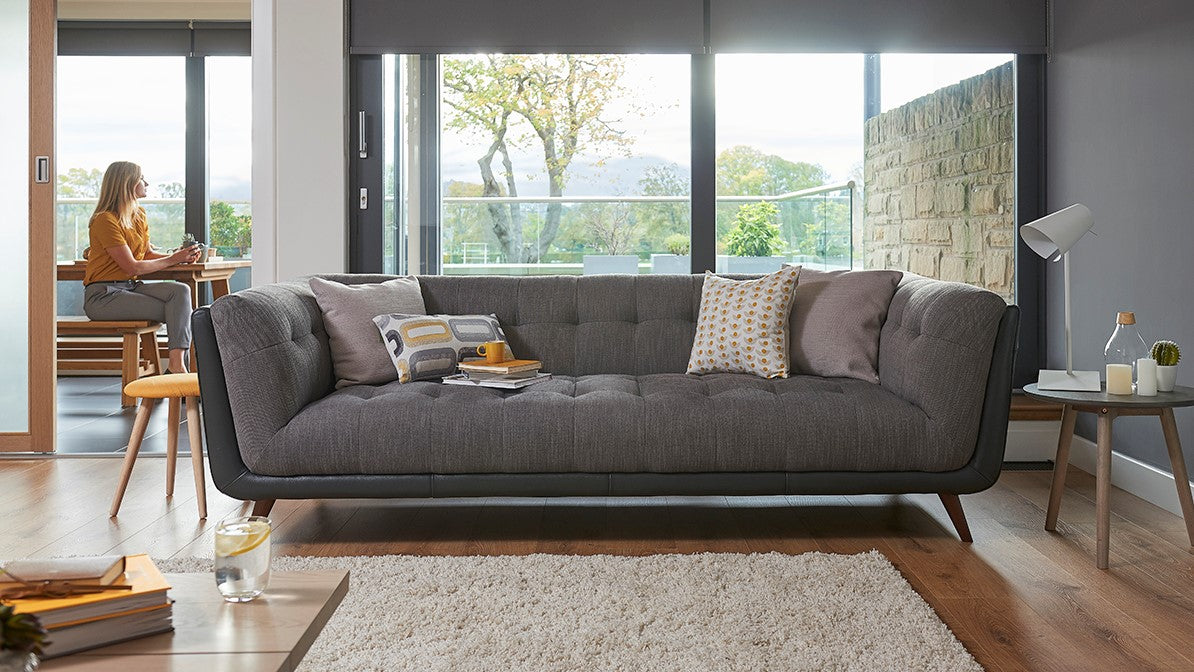 Modern living room with a grey sofa, coffee table, and large windows.