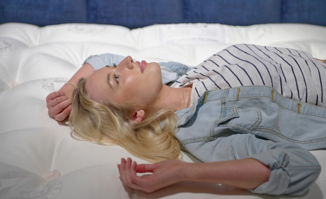 Woman lying on a white mattress with a blue headboard
