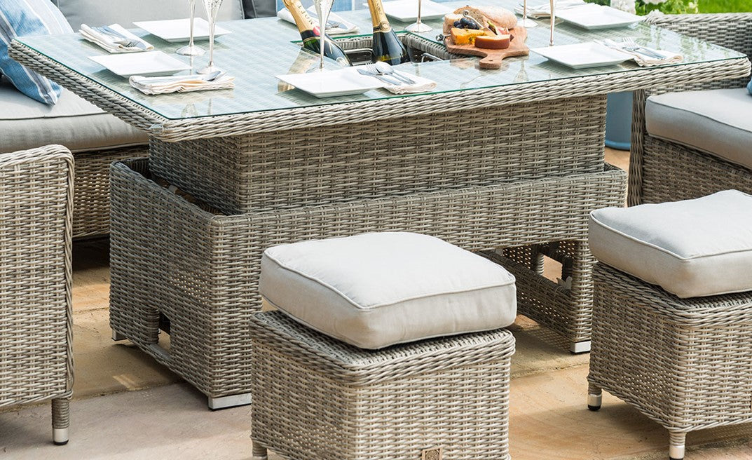 Outdoor rattan furniture set with a rattan table and stools with cushions.