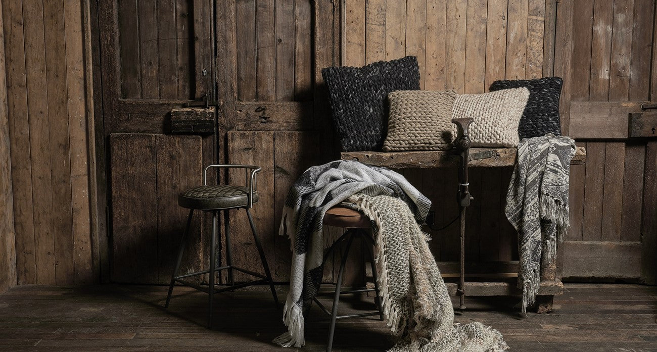 Metal stools with leather seat, throws and pillows in a rustic setting.